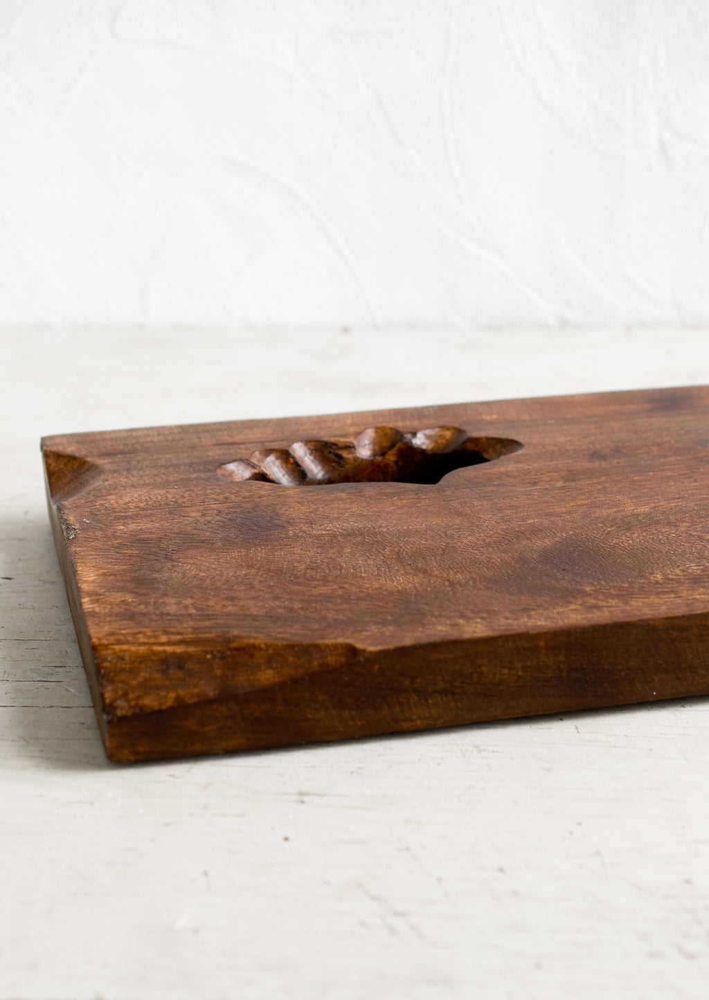 2: A rectangular wooden cutting board with knot cutout detail.