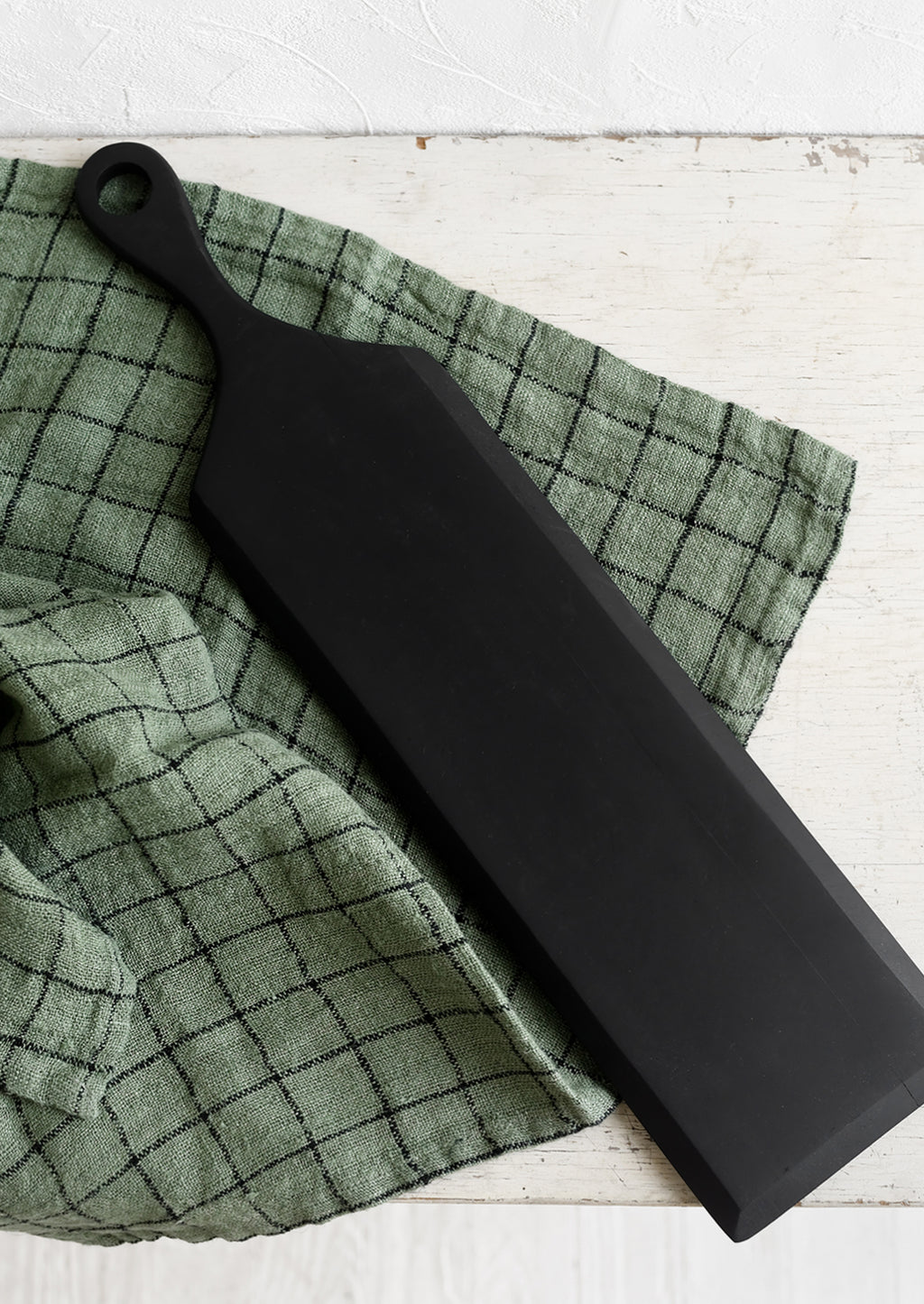 Slim: A long and thin paddle-shaped cutting board in black.