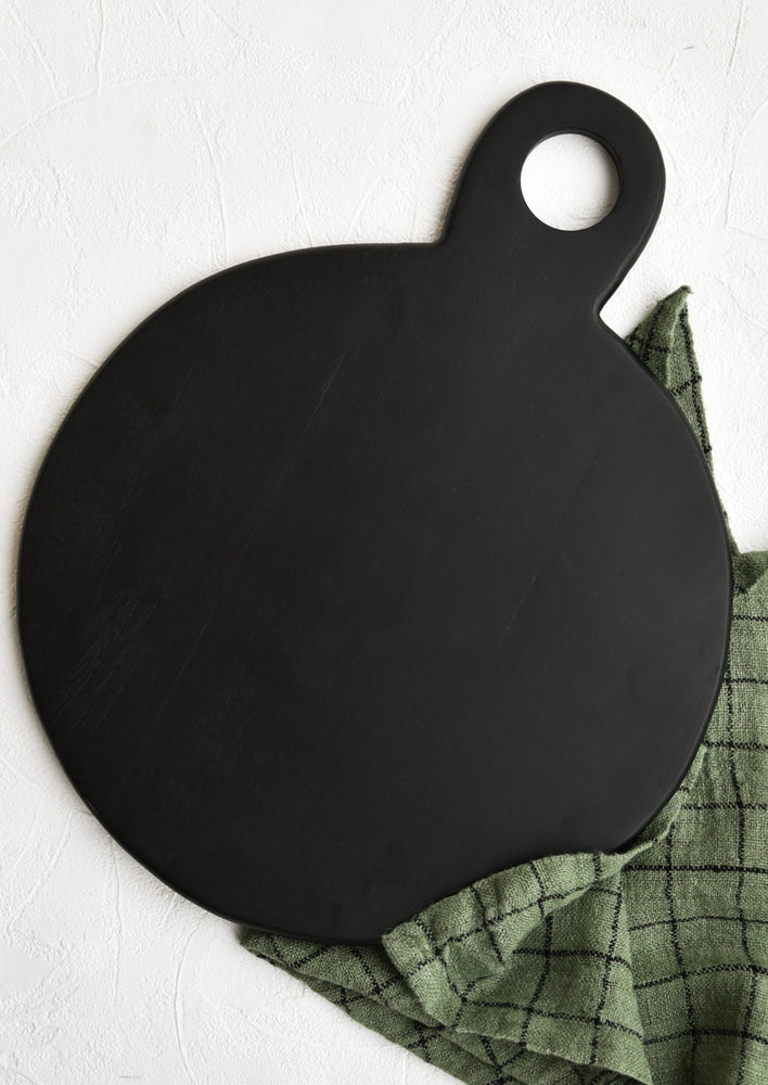 A wide, round cutting board in black.