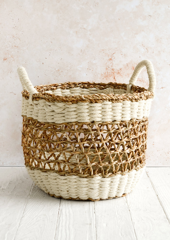 A medium open-top round storage basket made from seagrass with braided jute, featuring two handles at top.
