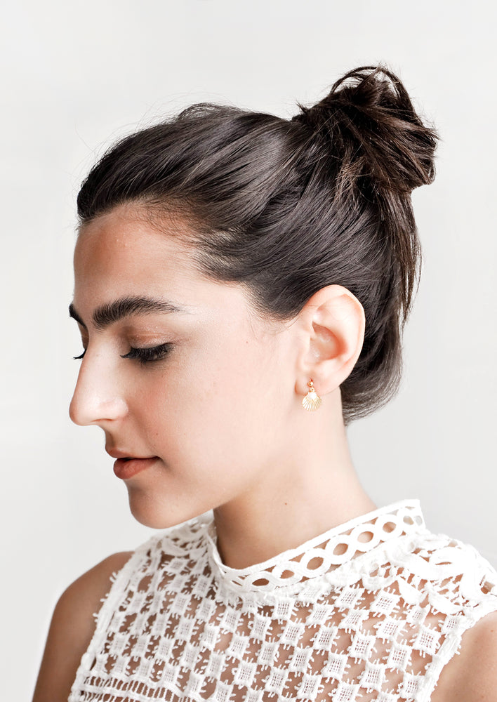 Model shot showing woman wearing earrings and white top.