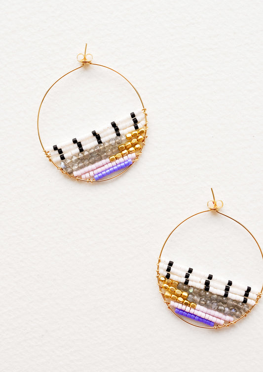 Thin gold hoop earrings with beads in white, black, gold, gray, and purple filling bottom half of hoop.