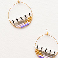 1: Thin gold hoop earrings with beads in white, black, gold, gray, and purple filling bottom half of hoop.