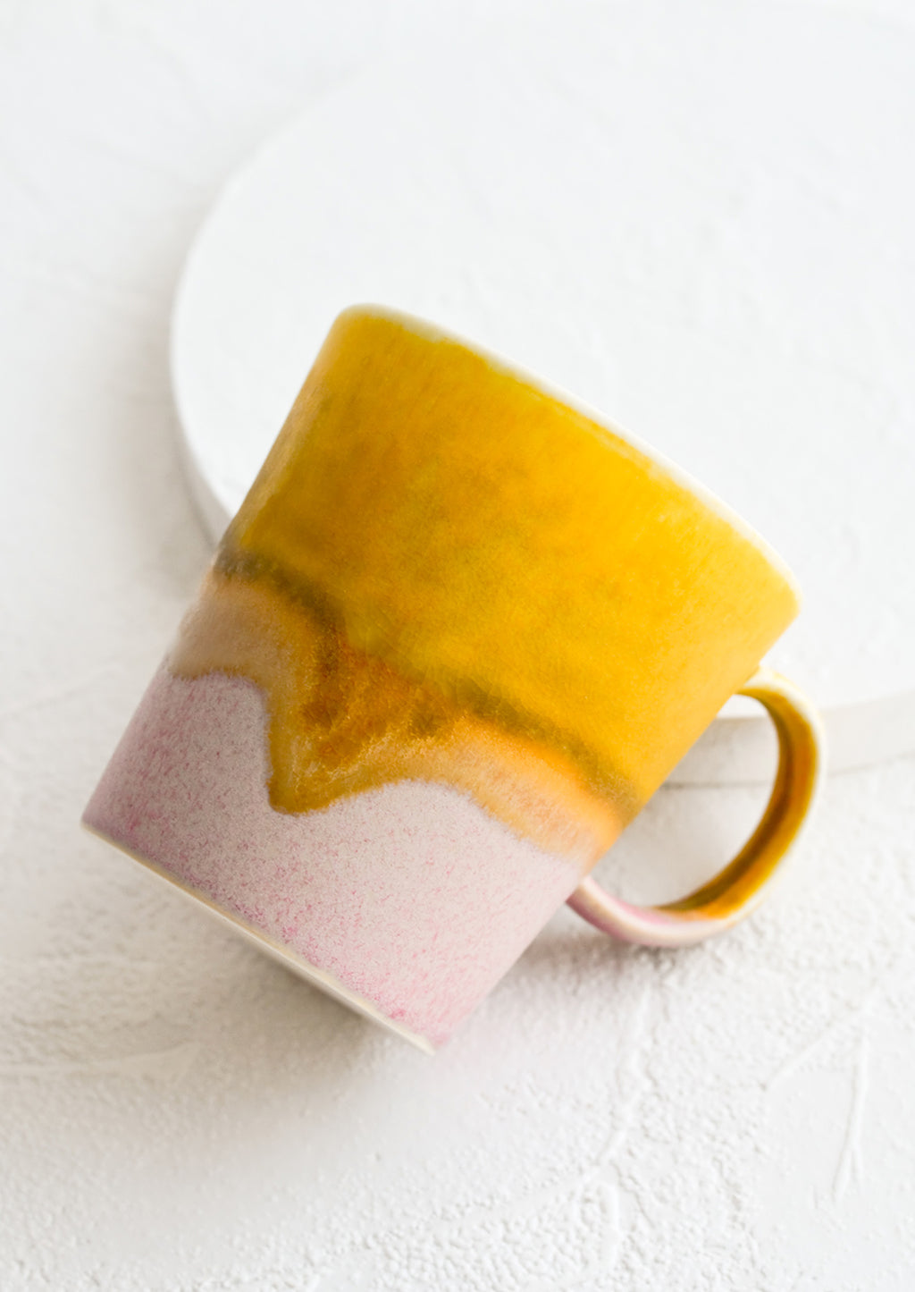 Mustard / Pink: A coffee mug with a handle in mustard and light pink.