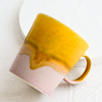 Mustard / Pink: A coffee mug with a handle in mustard and light pink.