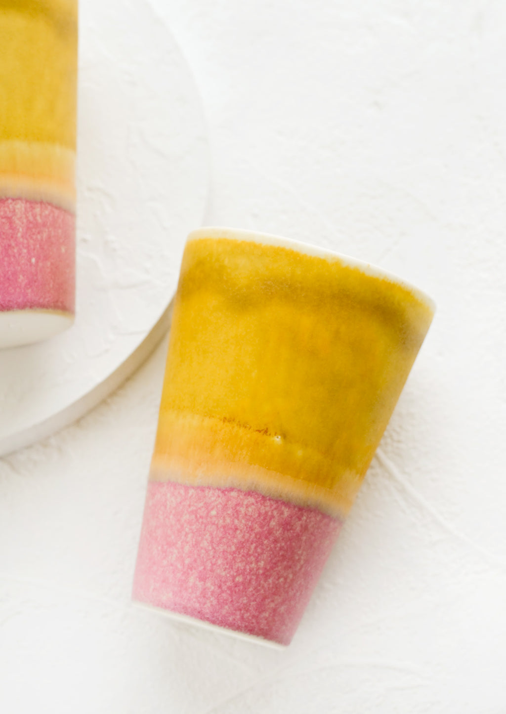 Mustard / Dark Pink: A ceramic cup in yellow and pink.