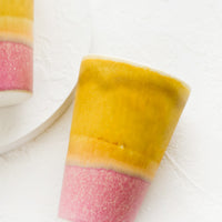 Mustard / Dark Pink: A ceramic cup in yellow and pink.