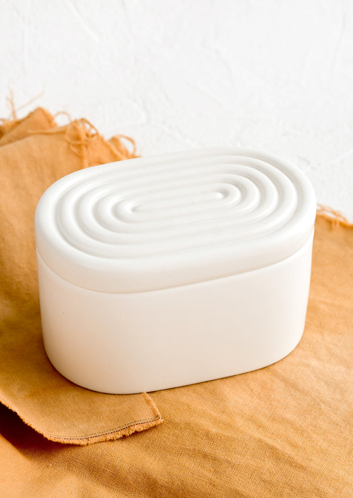 2: An oval-shaped white ceramic storage box with maze-patterned lid.