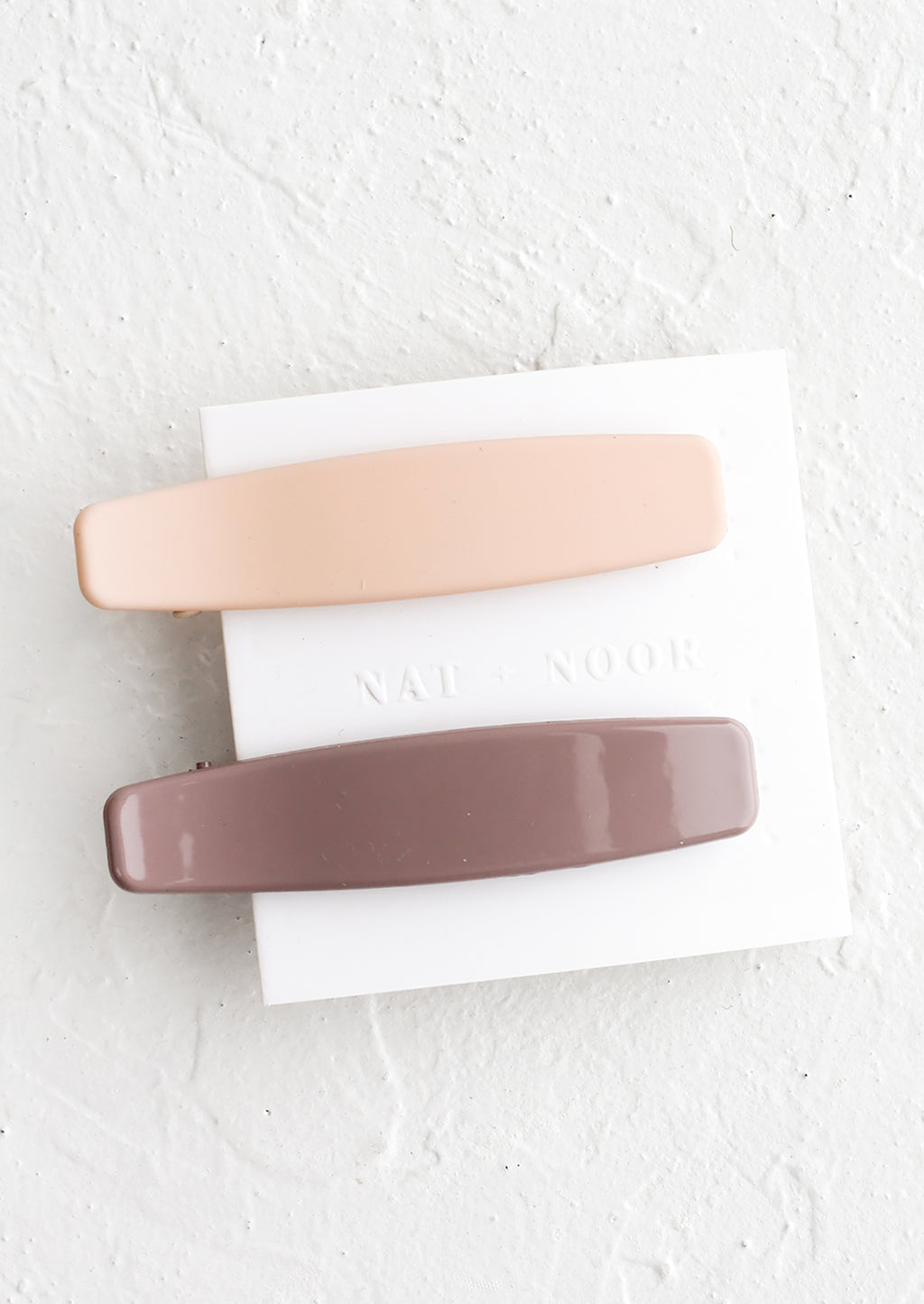 Nude / Mauve: A pair of hair clips with one nude and one mauve.