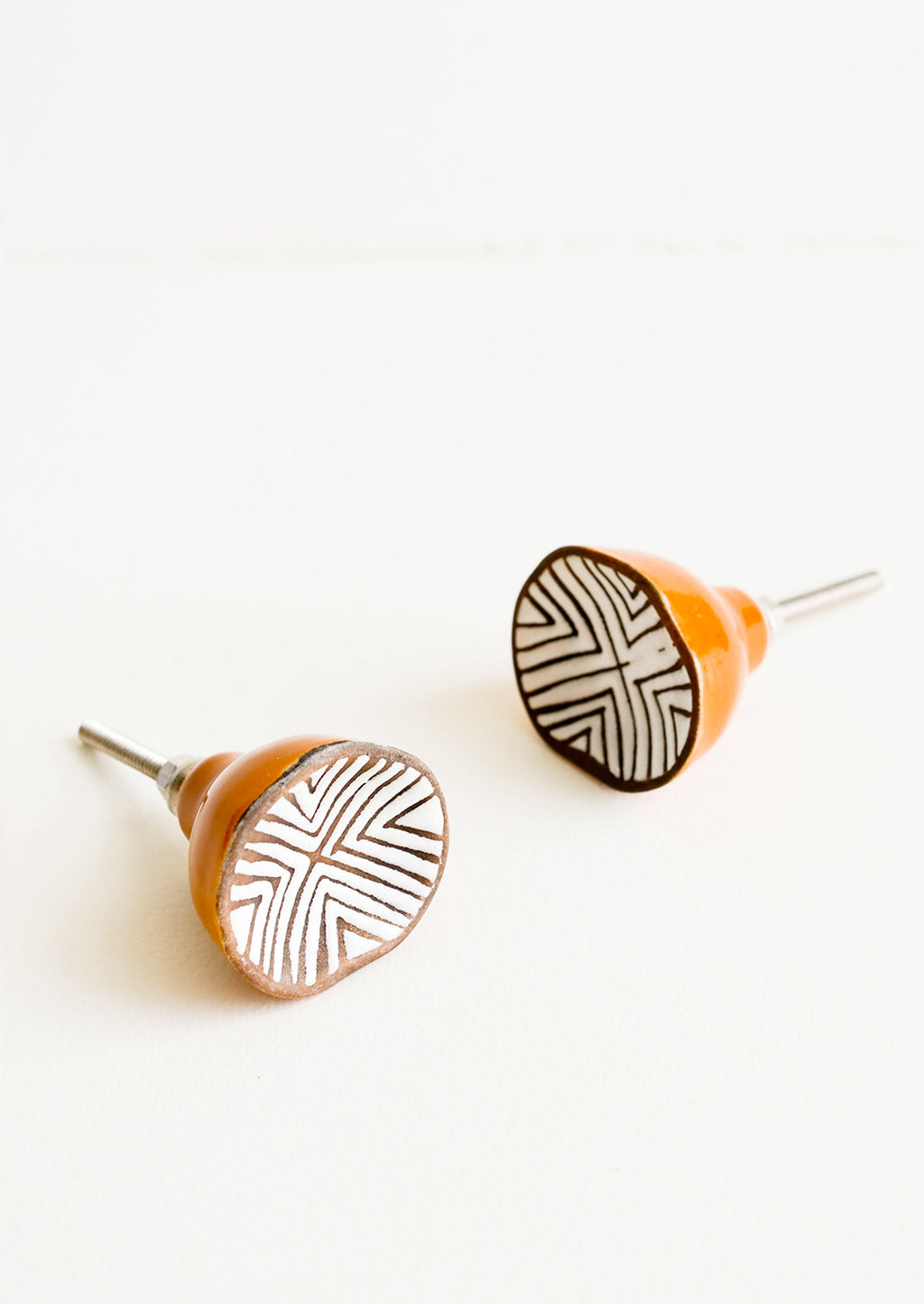 1: Round ceramic cabinet knobs with brown base and white chevron patterned front.