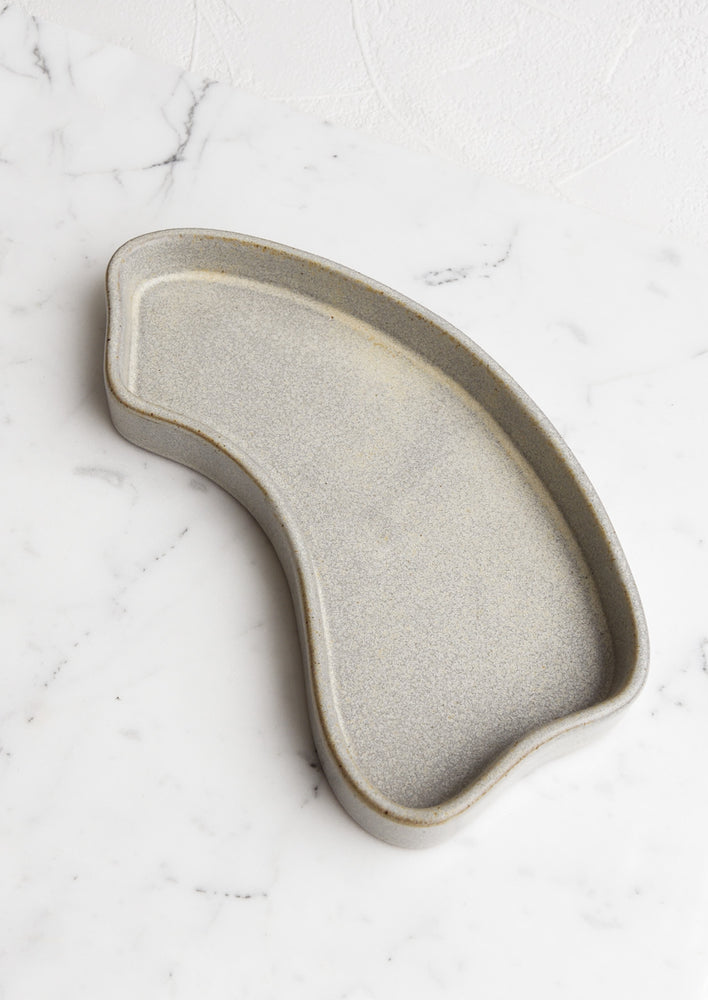 An asymmetrical medium sized ceramic tray in textured gray.