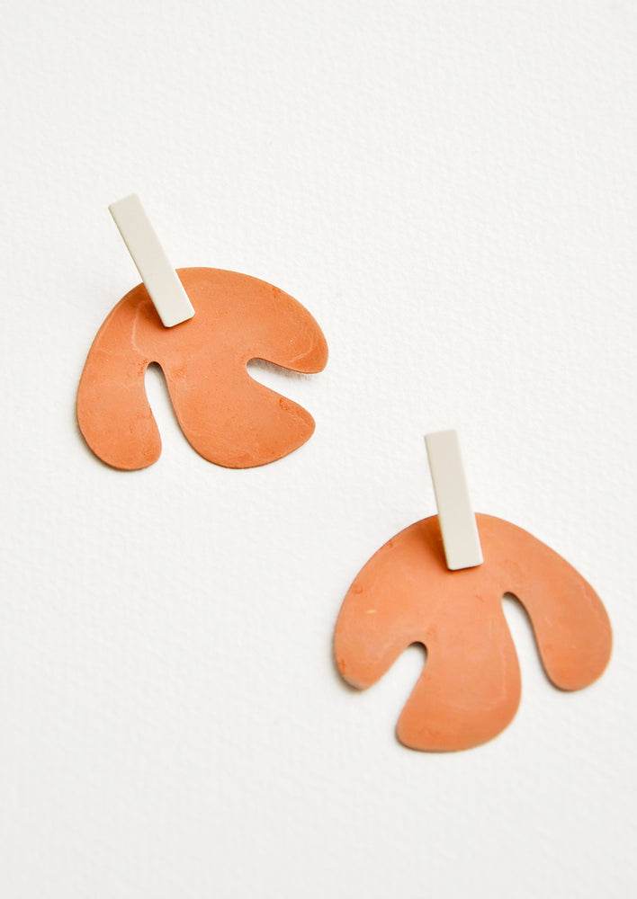 Post earrings with orange asymmetric leaf shape hanging from small silver rectangle.