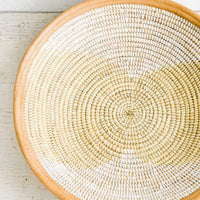 1: A woven seagrass and white plastic bowl with leather trim around top.