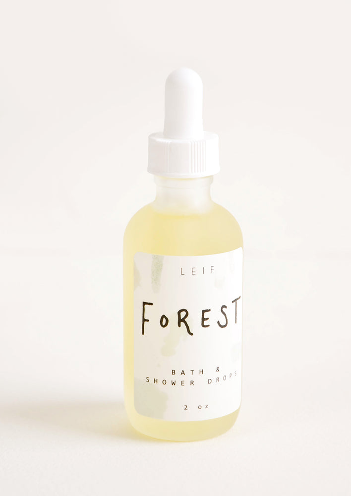 Forest: A small frosted glass dropper bottle with a white lid and a label reading "forest" filled with a pale yellow liquid.