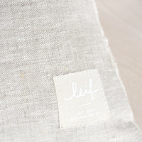 4: Natural linen with hand-stitched square logo patch at bottom corner.