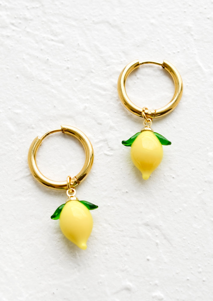 Gold huggie hoop earrings with glass lemon charms.