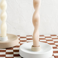 1: Taper candles and holders on a checkered tablecloth.