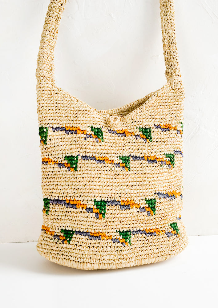A hobo tote made from natural raffia with green, purple and yellow detailing.