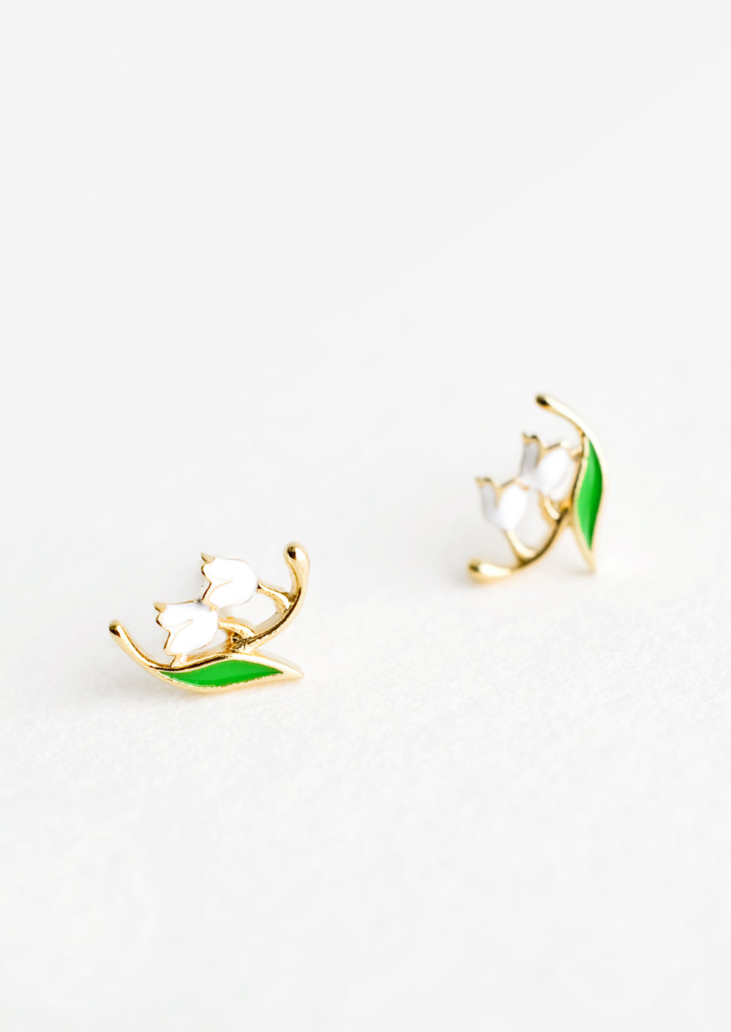 2: Small gold stud earrings in the shape of a lily of the valley flower, constructed in green and white enamel finish.