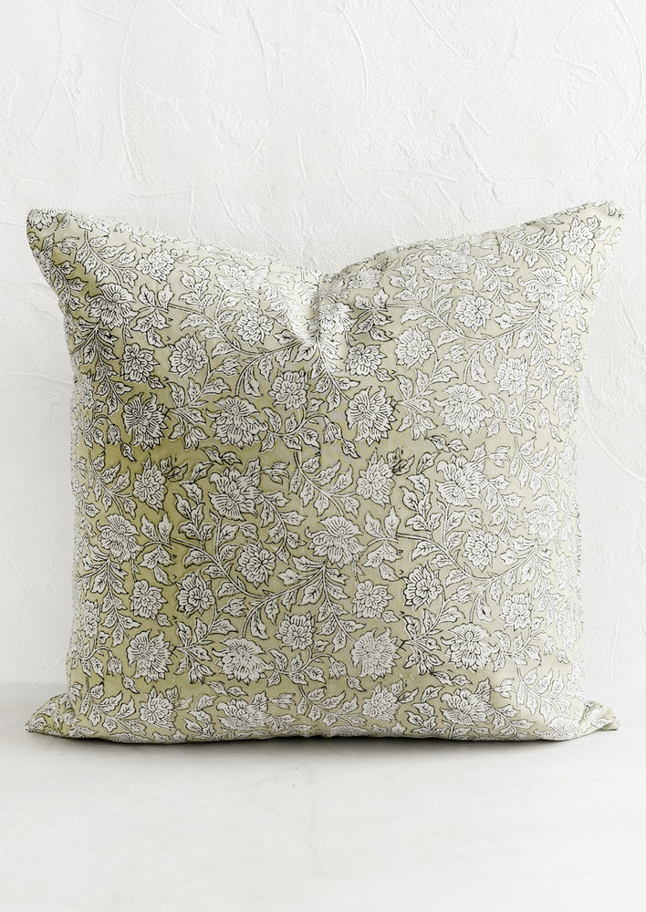 A throw pillow in greige floral block print fabric.