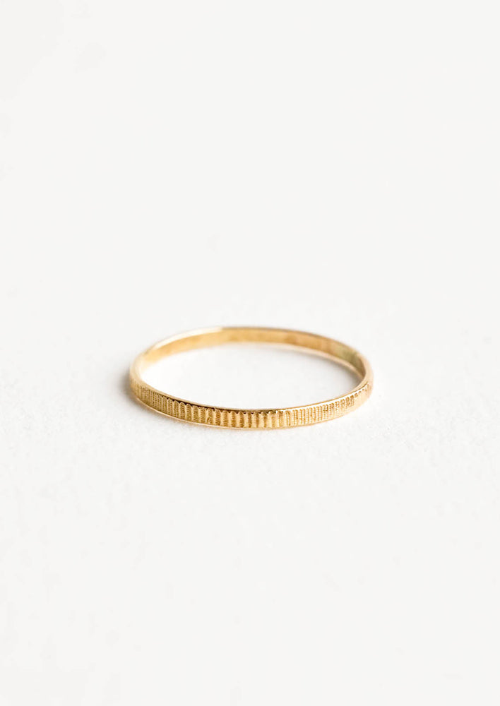Yellow gold ring with etched decorative markings around the band. 