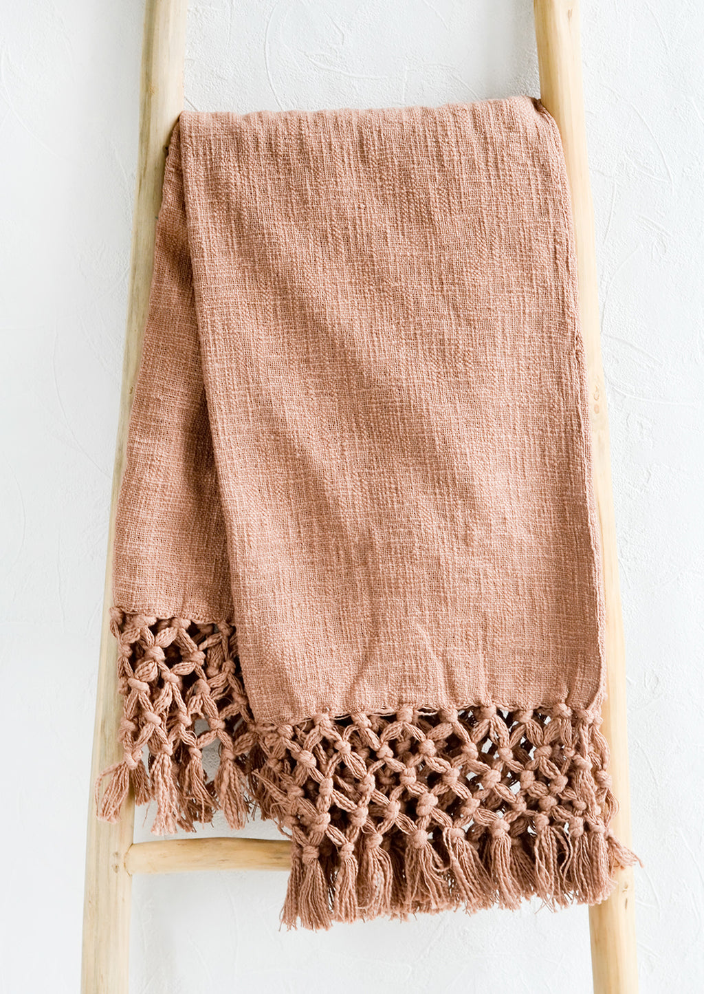 Clay: A muted red-brown cotton throw blanket with knotted open weave trim, displayed on a ladder.