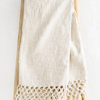 Ivory: An ivory cotton throw blanket with knotted open weave trim, displayed on a ladder.