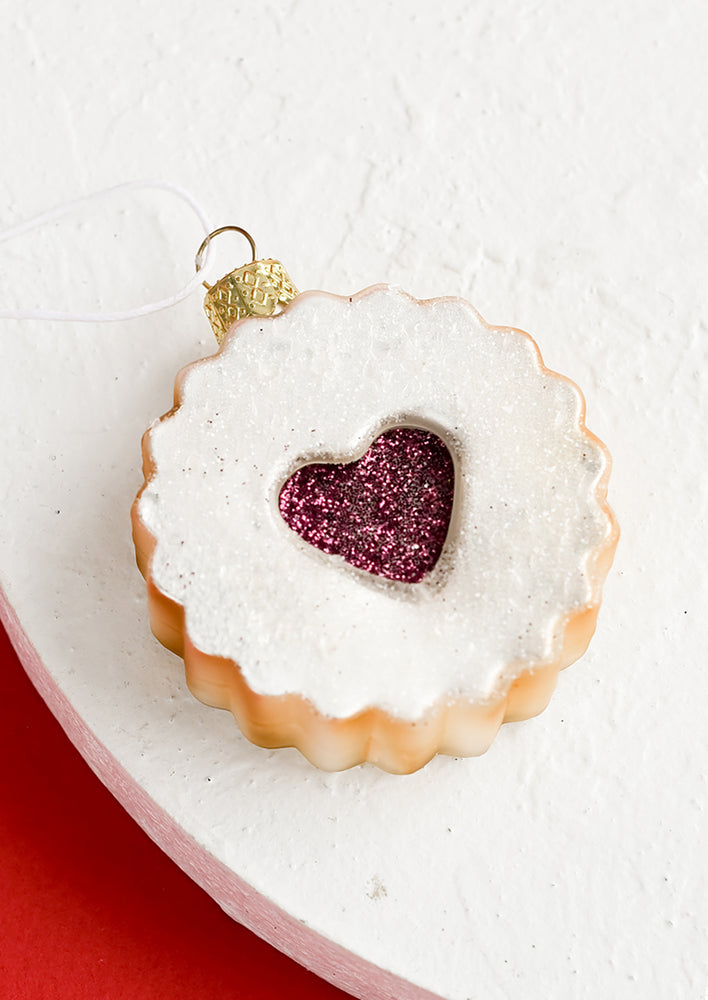 1: A glass holiday ornament in shape of raspberry linzer cookie with heart center.