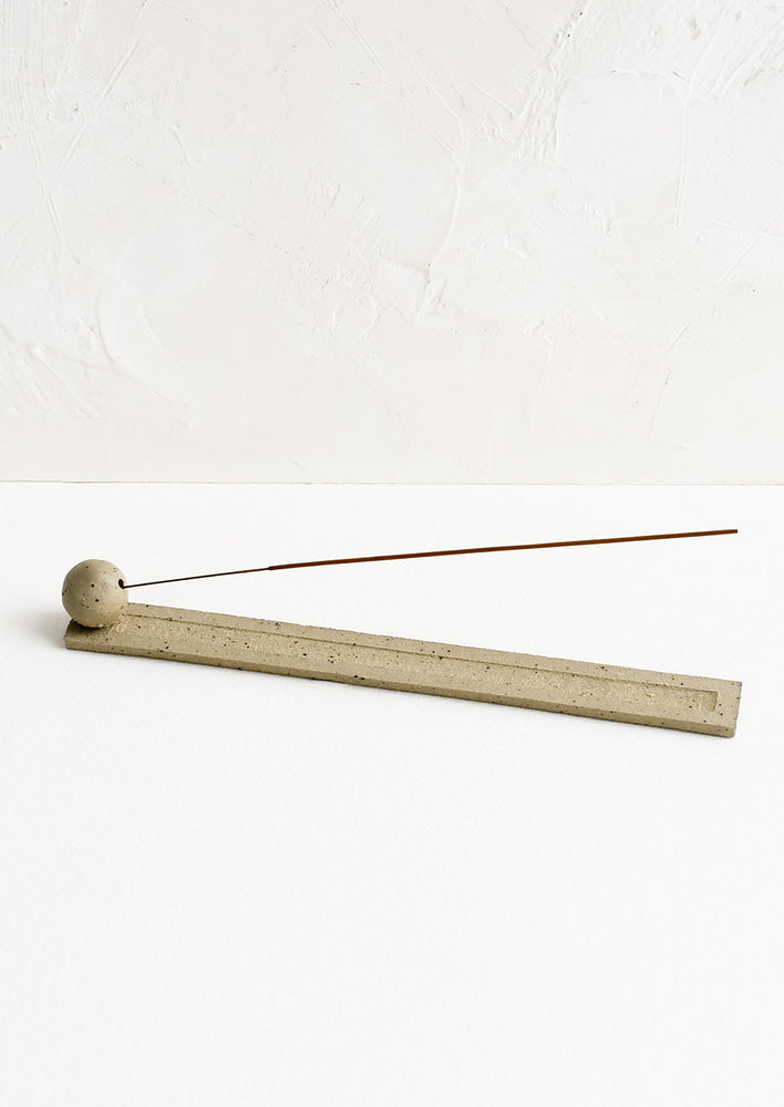 A long, skinny ceramic incense holder with ball detail at one end.