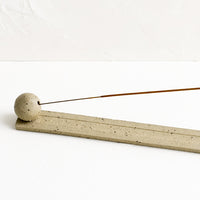 2: A long, skinny ceramic incense holder with ball detail at one end.