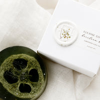Heirloom Herb: A round translucent green bar soap with wax seal packaging.