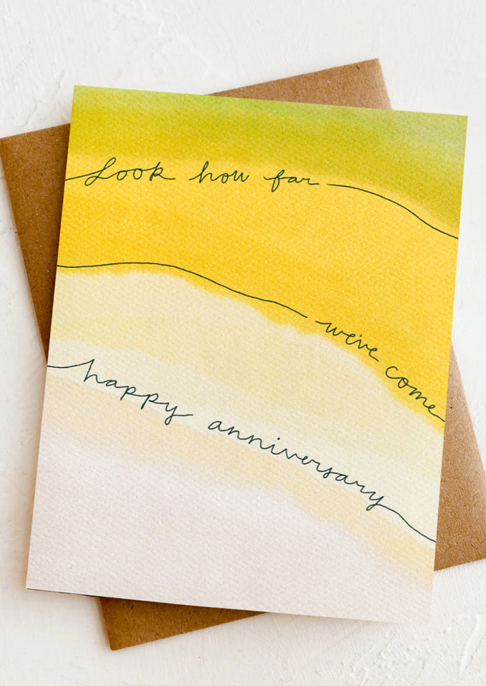 A watercolor card reading "look how far we've come, happy anniversary".
