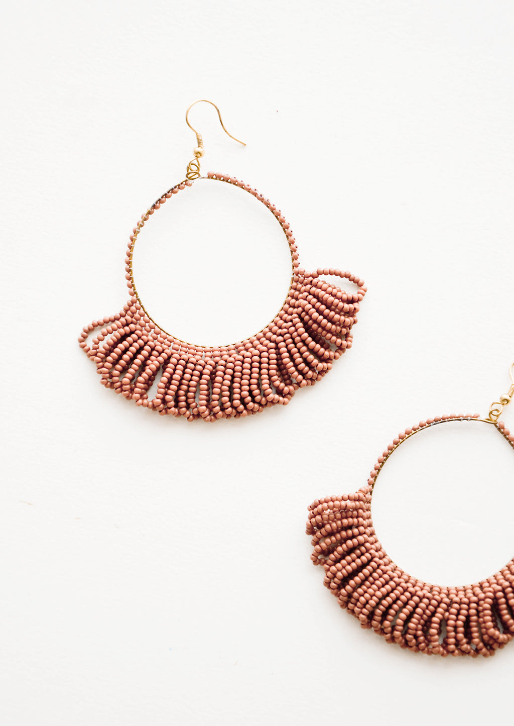 Clay: Dangling hoop earrings featuring clay red beads and accented with hanging beaded, looped fringe.