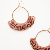 Clay: Dangling hoop earrings featuring clay red beads and accented with hanging beaded, looped fringe.