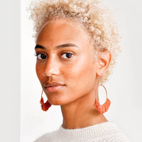 2: Model shot of woman wearing earrings and a white top. 