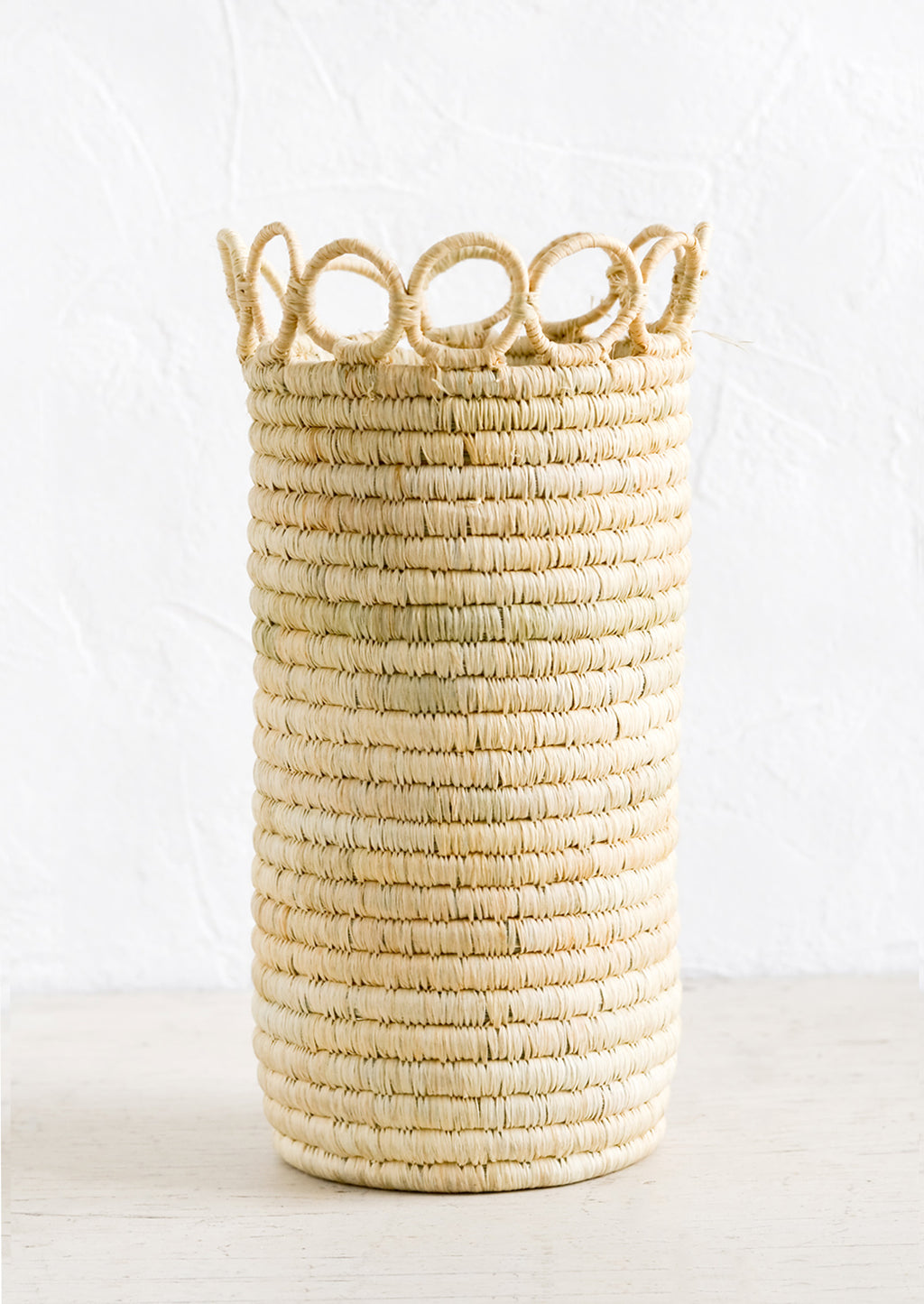 1: A tall, cylindrical vase in natural raffia with open circle trim along top.