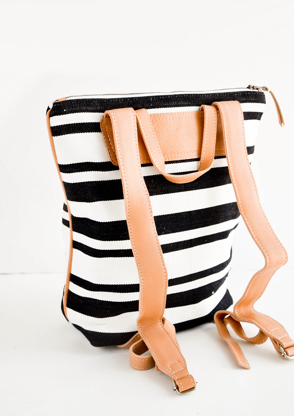 3: Tanned leather straps on the back of black & white striped canvas backpack