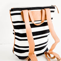 3: Tanned leather straps on the back of black & white striped canvas backpack