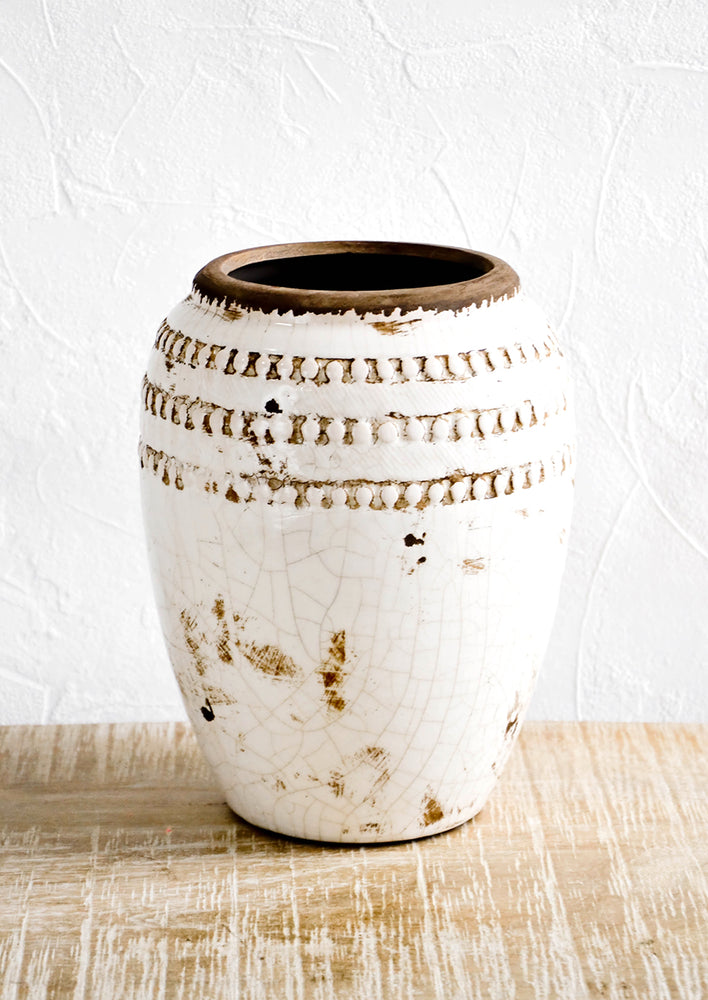 Distressed urn-shaped ceramic vase with glossy, crackled cream glaze and brown textured detailing