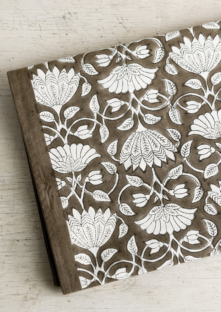 2: A block printed tablecloth with white lotus print on brown background.