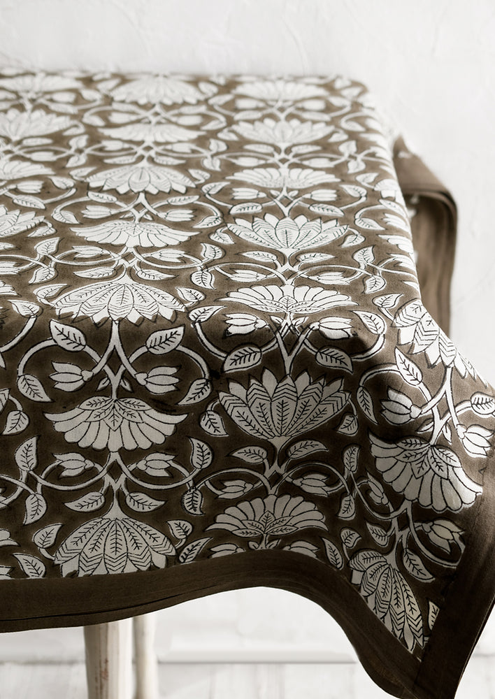 A block printed tablecloth with white lotus print on brown background.