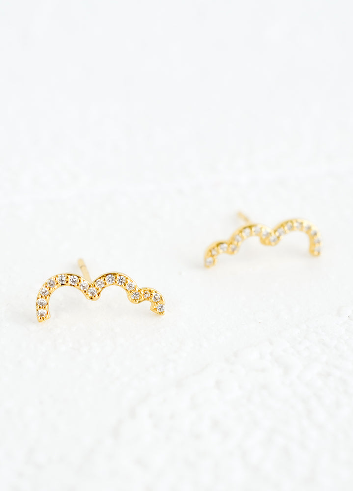 2: A pair of gold stud earrings in squiggly, half cloud-like shape with clear crystal detailing.