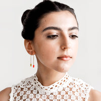 2: Model wears arced earrings and white blouse.