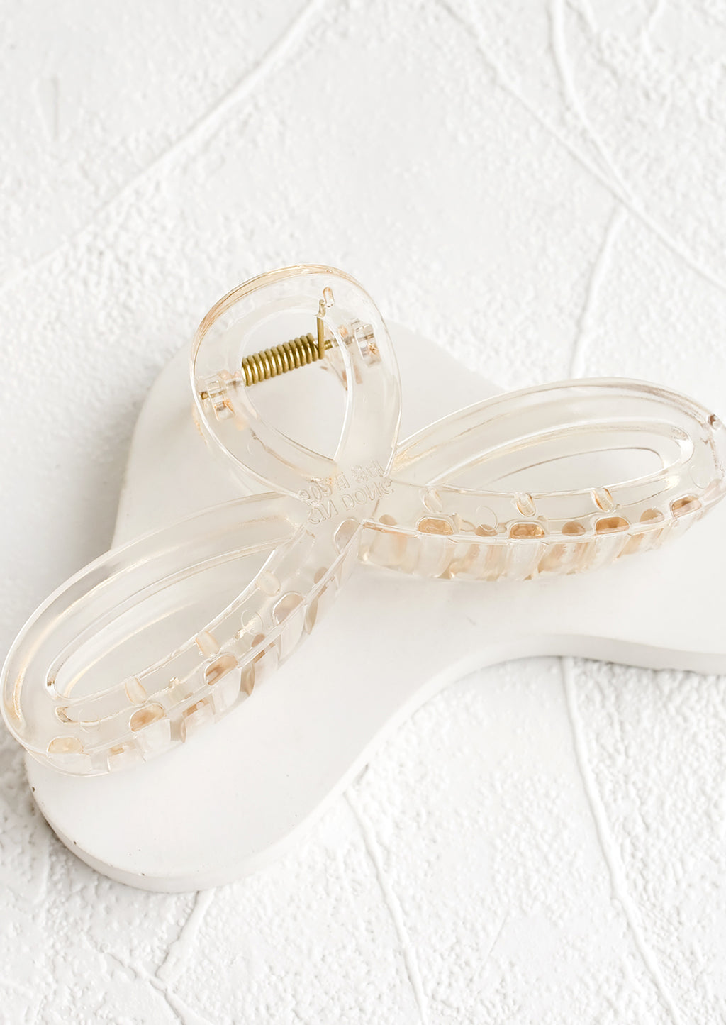 Pale Honey: A curvy hair clip with knotted loop design in shiny transparent pale brown.