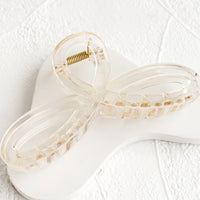 Pale Honey: A curvy hair clip with knotted loop design in shiny transparent pale brown.