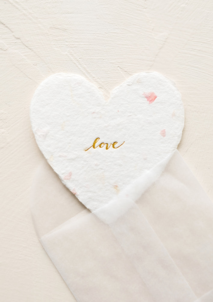 A small heart shaped card made from flower petal paper with gold "love" text in cursive.