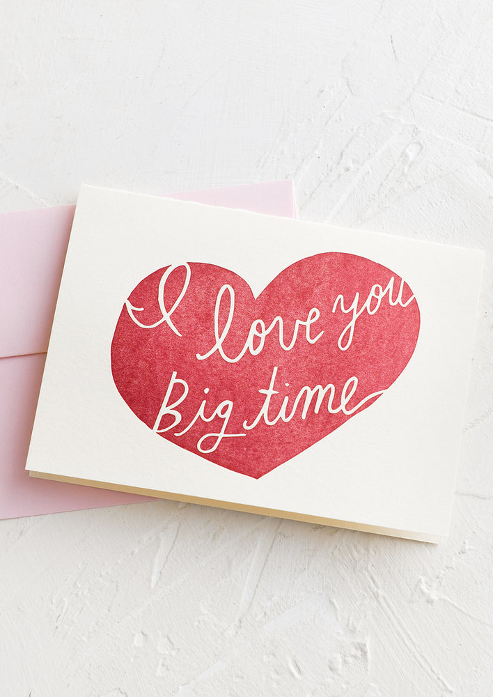 A greeting card with red heart reading "I love you big time".