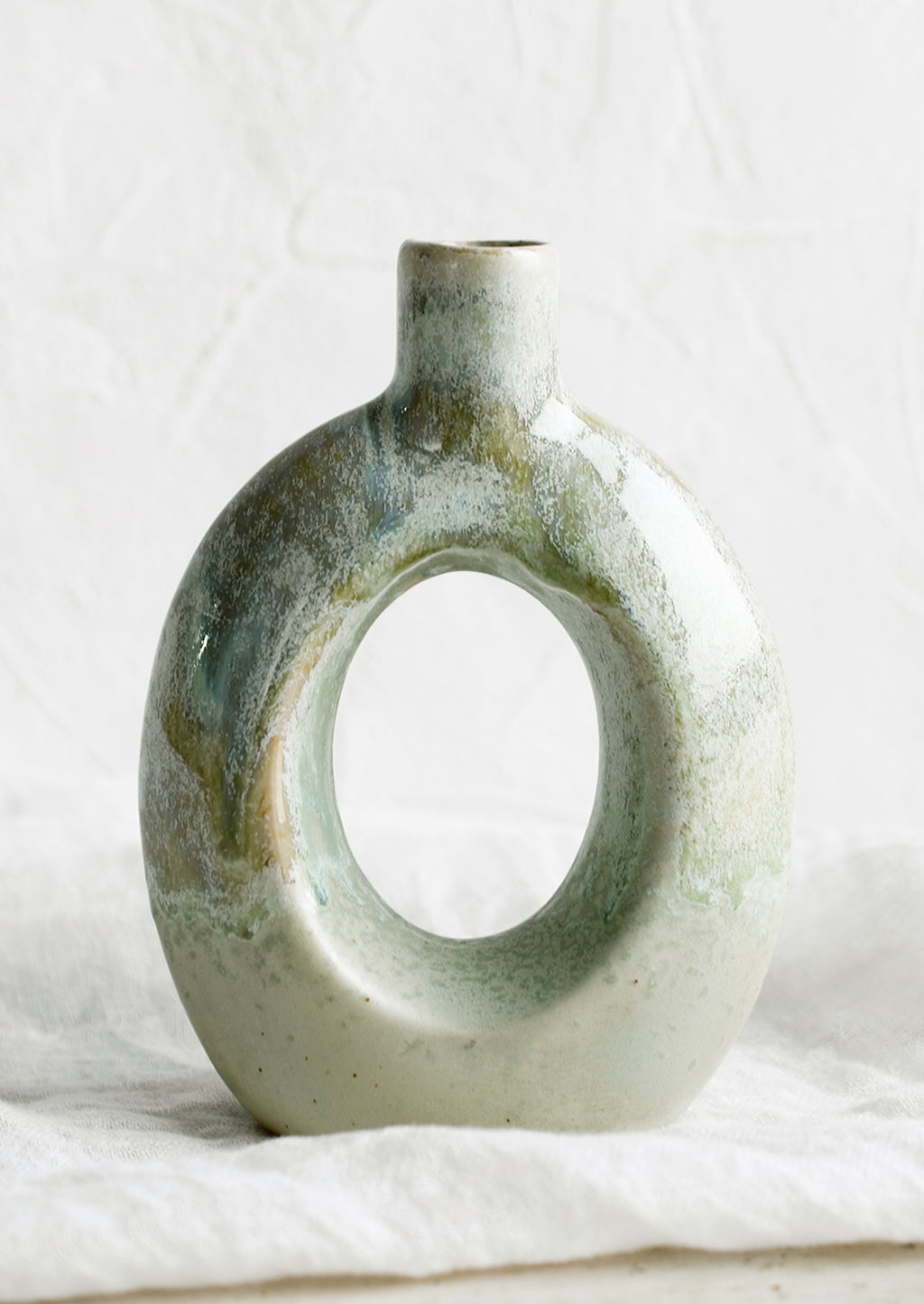 Oval: A ceramic vase in mottled aqua glaze with hollow oval shape.
