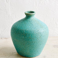 1: A textured turquoise ceramic bud vase with tapered top.
