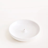 2: A simple white dish with a small hold at the center for holding incense.